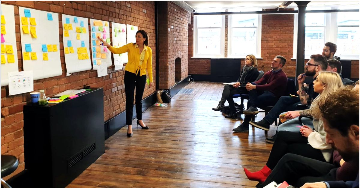 Marina Nicholas working a wall of post-it notes with a client team
